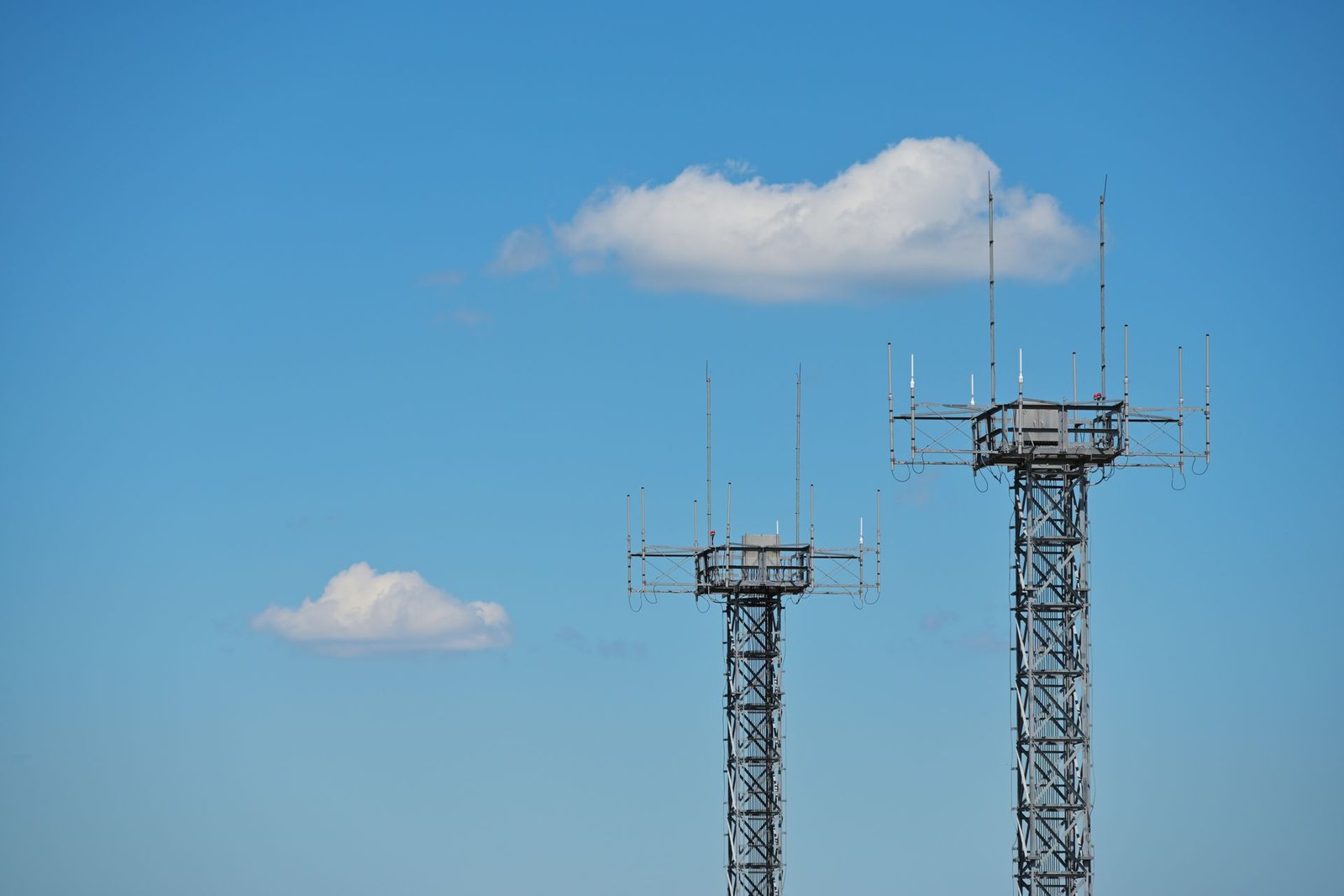 Duas torres metálicas de telecomunicações com antenas recortadas contra o céu azul