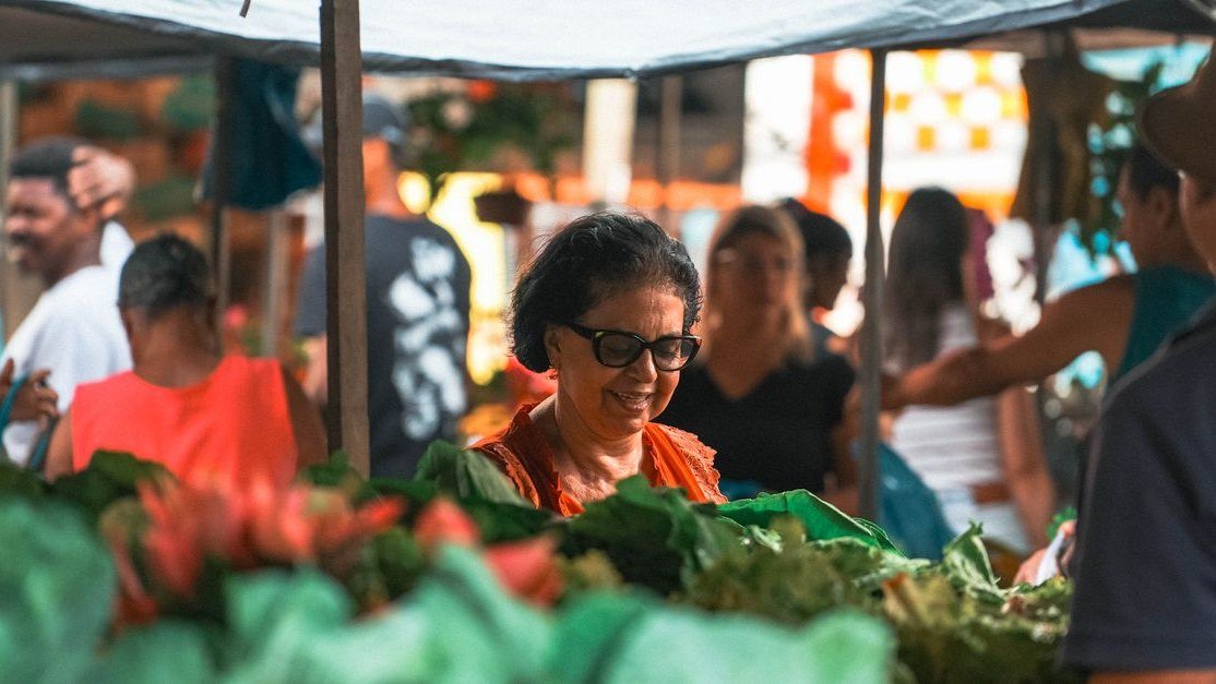 Consumidora observa verduras frescas em banca de feira livre no Brasil