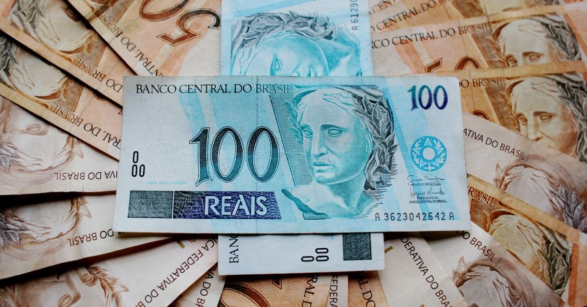Notas de cem e cinquenta reais espalhadas sobre uma superfície