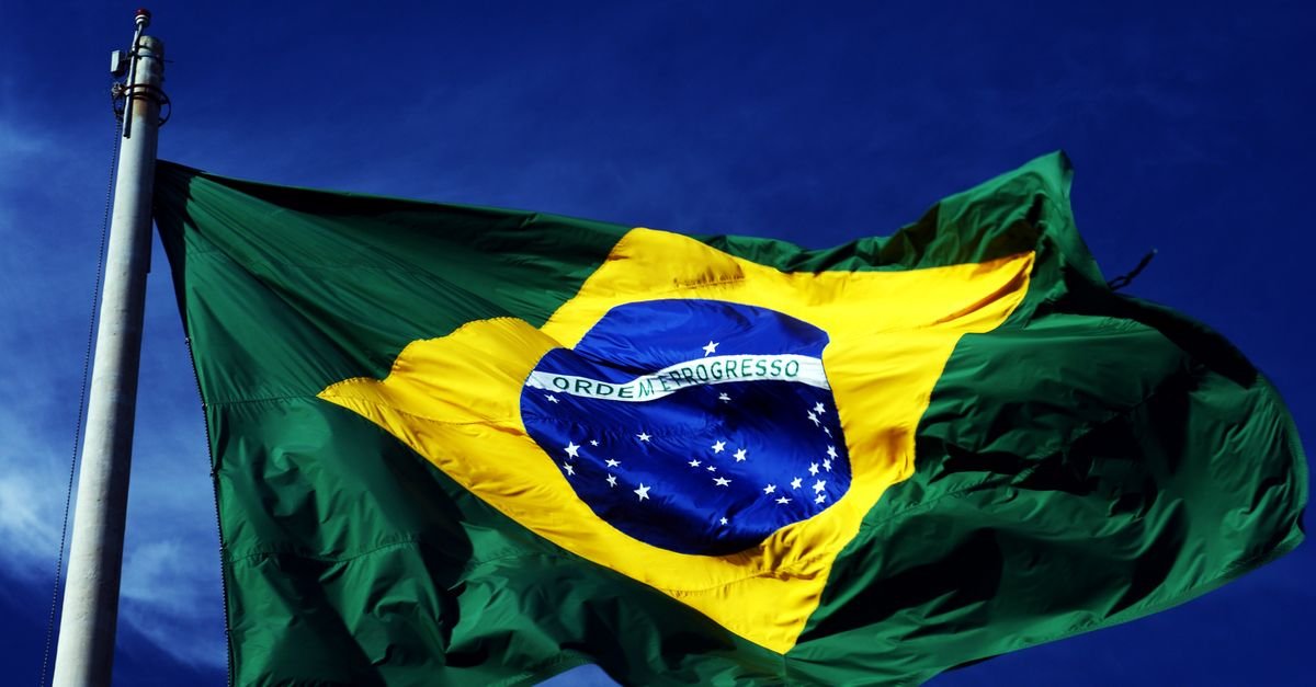 Bandeira do Brasil hasteada em mastro contra o céu azul