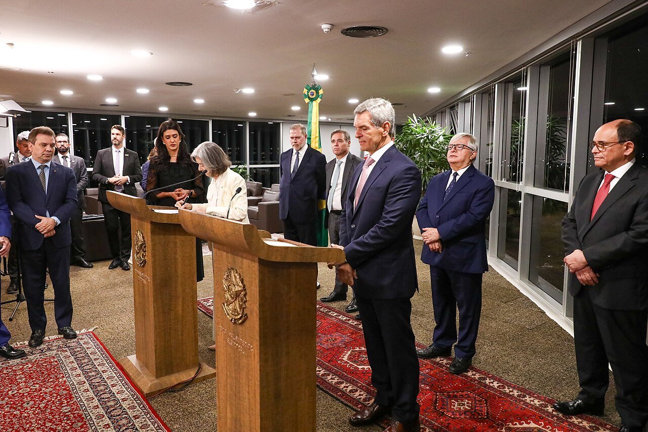 Ministro Marco Aurélio Bellizze em pé diante de dois púlpitos durante a posse como ministro substituto do TSE, em abril de 2026, ao lado da ministra Cármen Lúcia
