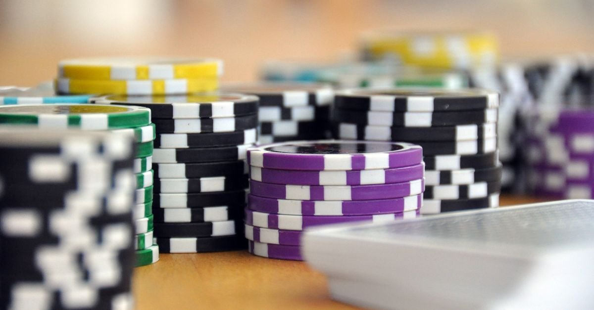 Pilhas de fichas de poquer coloridas e um baralho de cartas sobre mesa de madeira