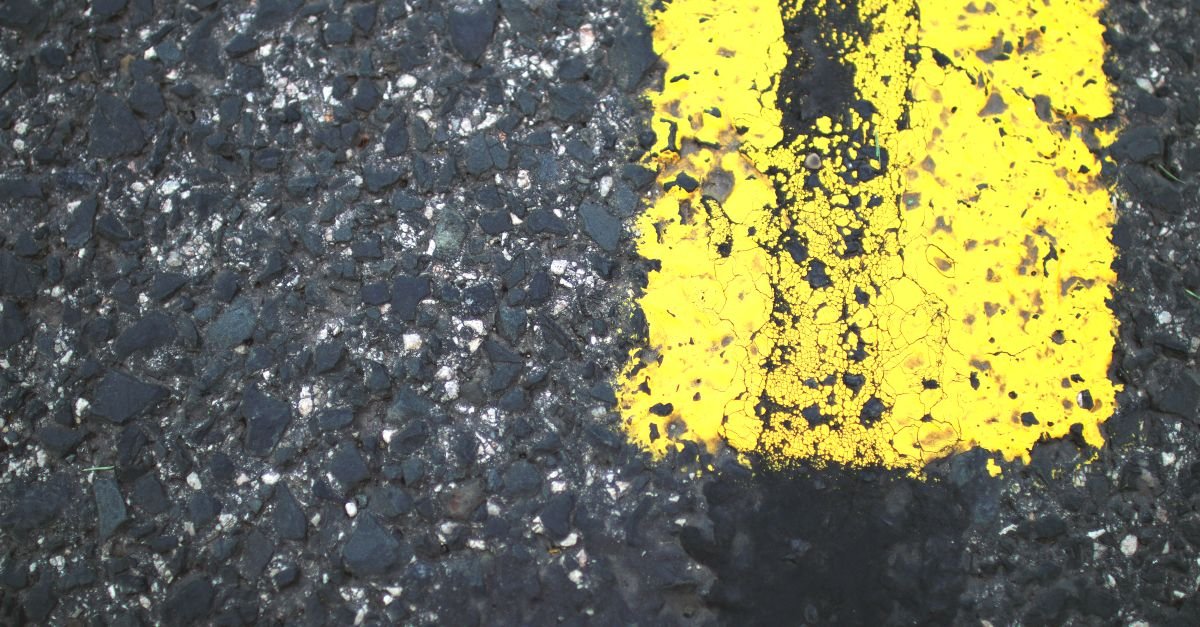 Faixa amarela continua pintada sobre o asfalto de uma rodovia