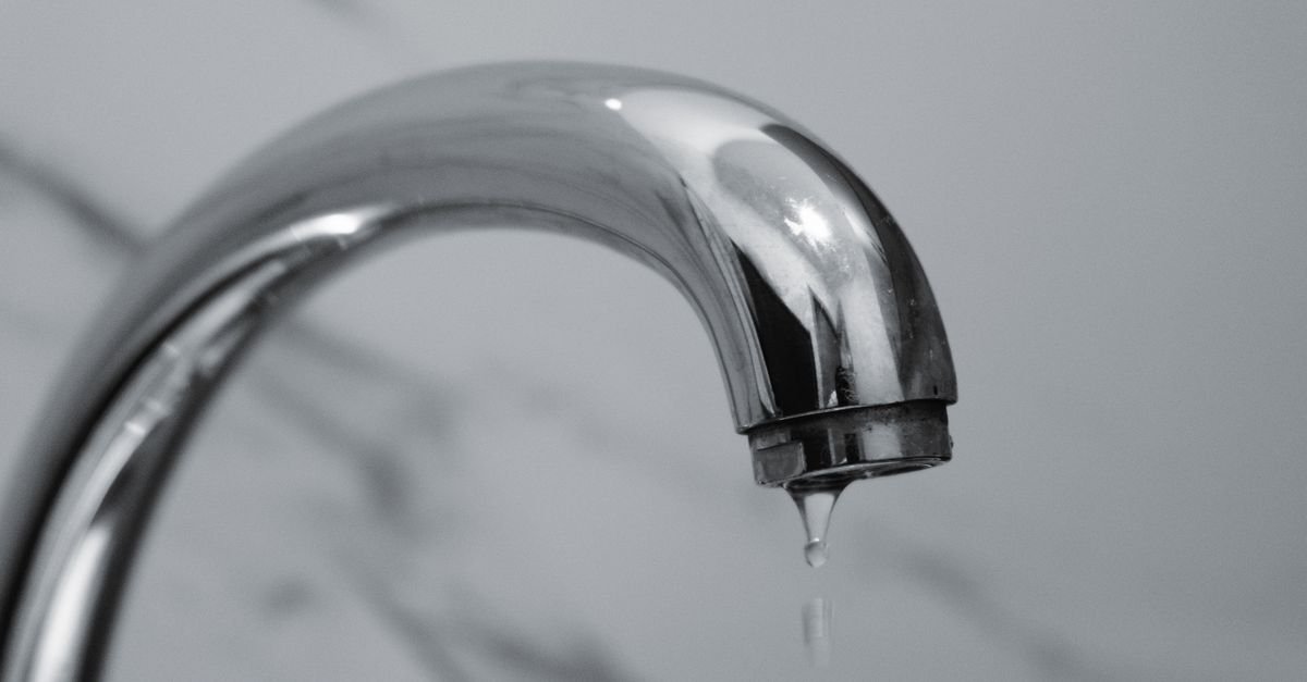 Torneira cromada com gota de água prestes a cair