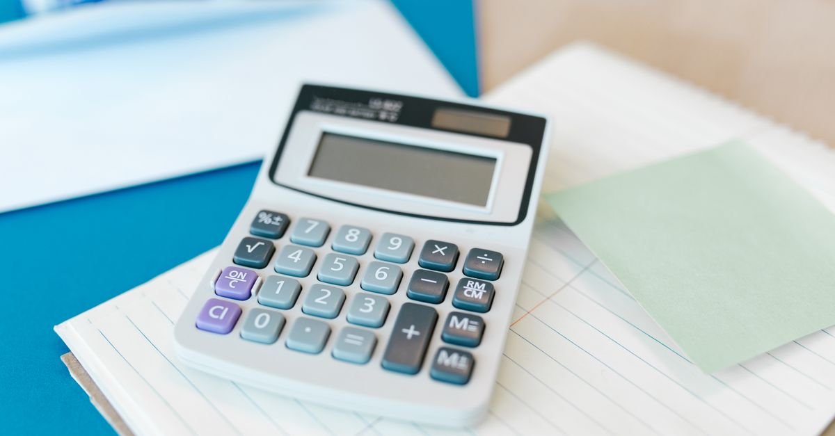 Calculadora branca apoiada sobre bloco de papel pautado em mesa de escritório