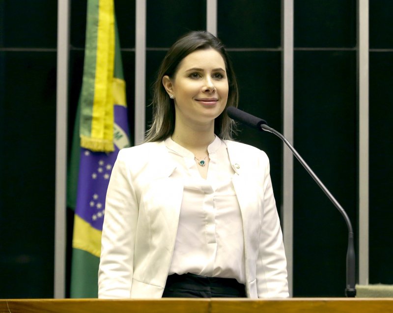 A deputada federal Caroline de Toni na tribuna da Câmara dos Deputados, com a bandeira do Brasil ao fundo