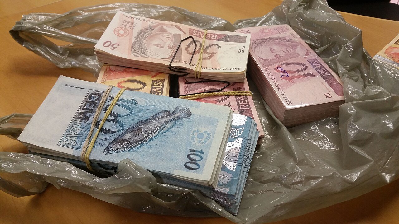 Maços de cédulas de real sobre mesa, em imagem ilustrativa de recursos públicos