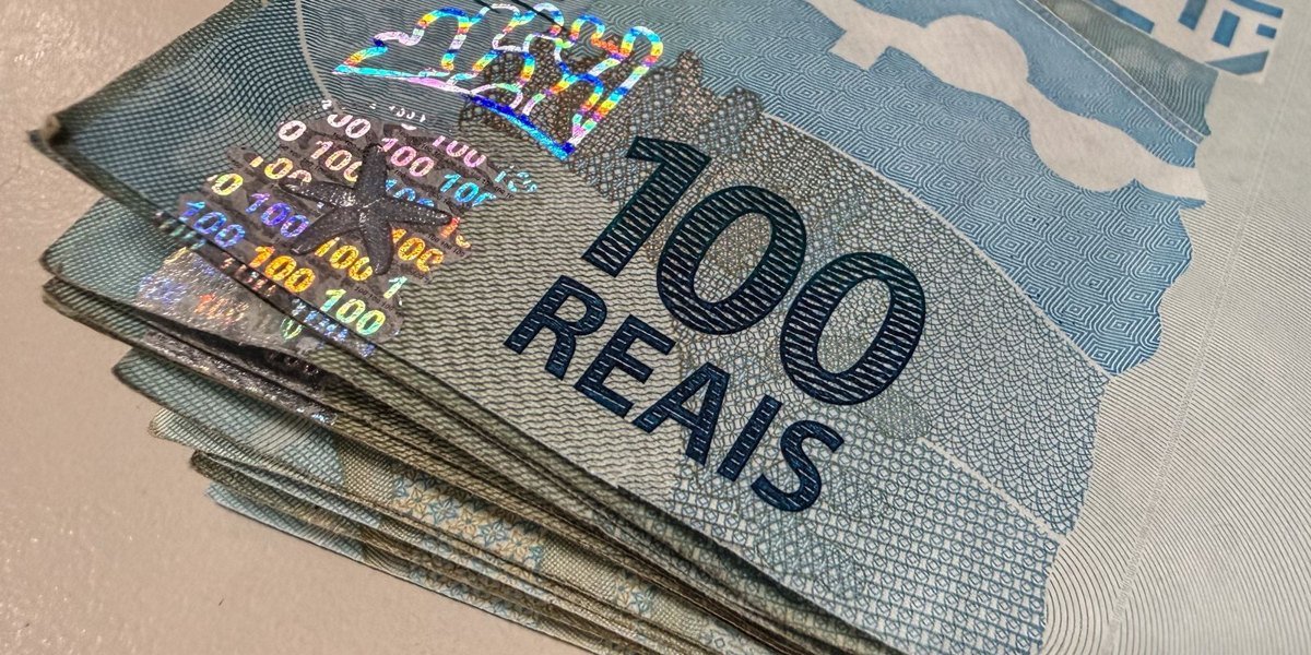 Maço de cédulas de cem reais em closeup sobre superfície clara