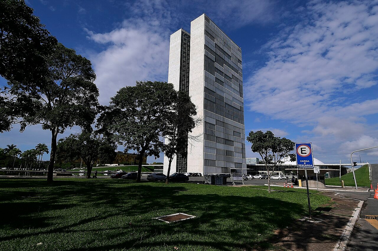 Fachada do Palácio do Congresso Nacional em dia de céu azul, vista do gramado