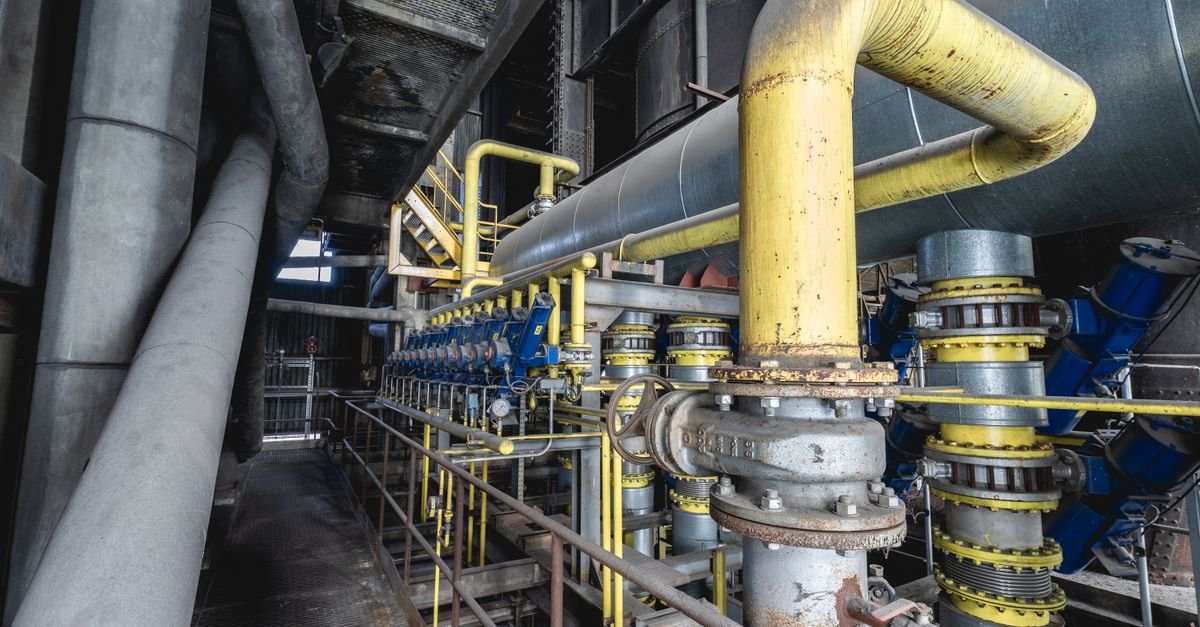 Tubulação industrial de gás com dutos amarelos, válvulas e flanges em uma planta de processamento