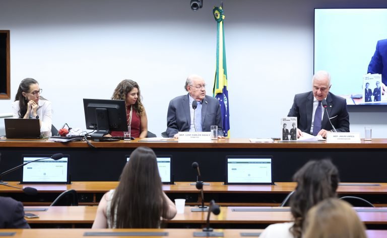 Deputados reunidos à mesa durante votação de relatório em comissão da Câmara dos Deputados