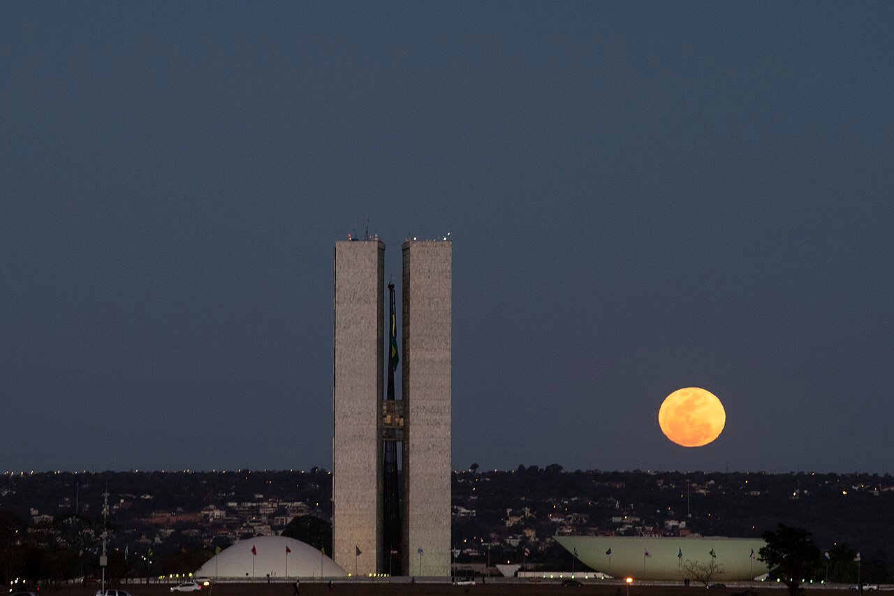 Torres do Congresso Nacional ao anoitecer, com a Lua ao lado, em Brasília
