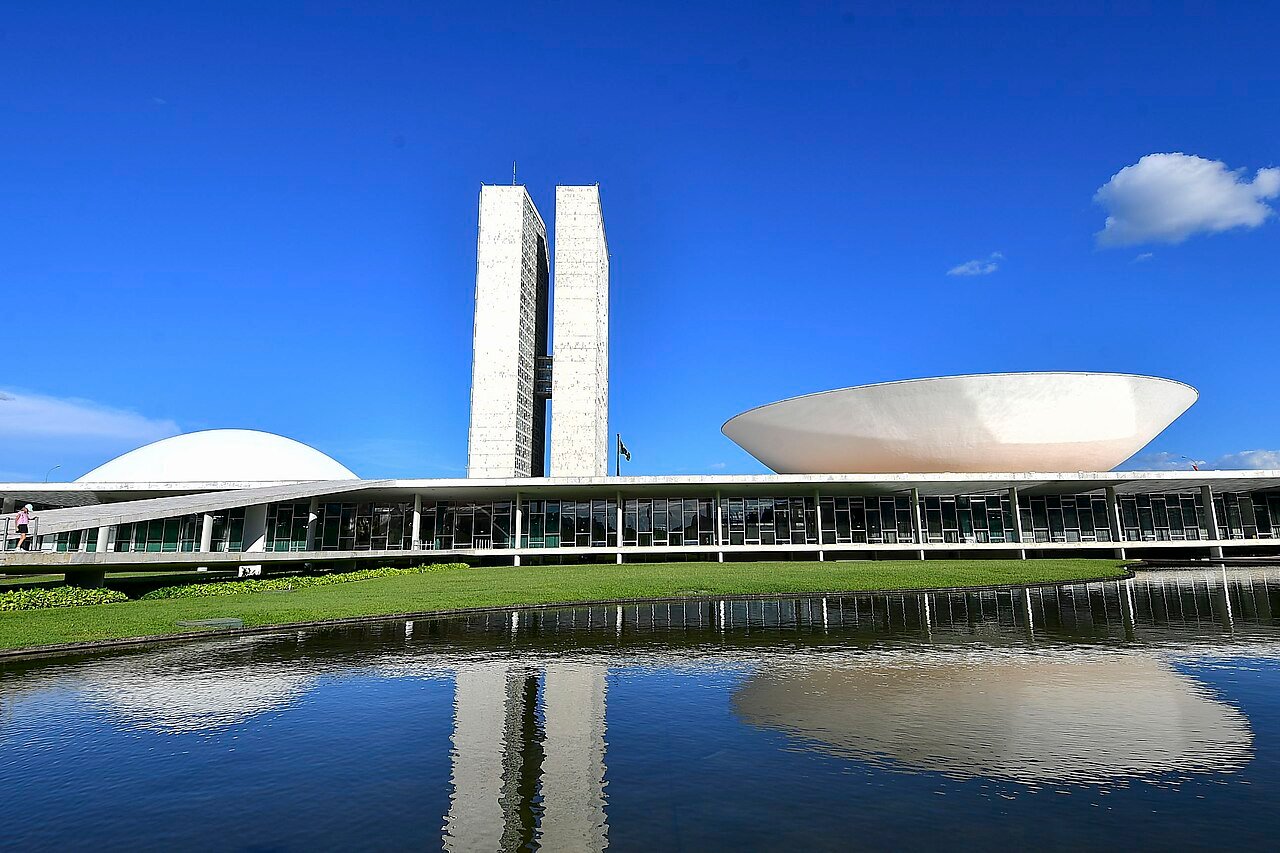 Fachada do Congresso Nacional, em Brasília, com as duas torres e as cúpulas refletidas no espelho d'água