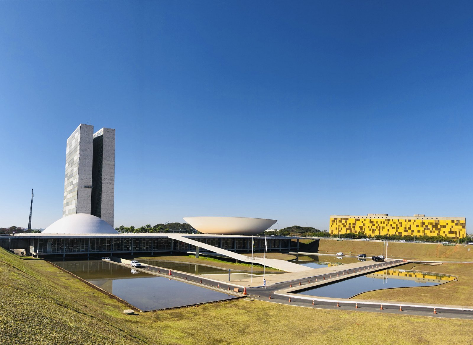 Palácio do Congresso Nacional visto do gramado, com as duas cúpulas e as torres ao fundo, em dia de céu limpo