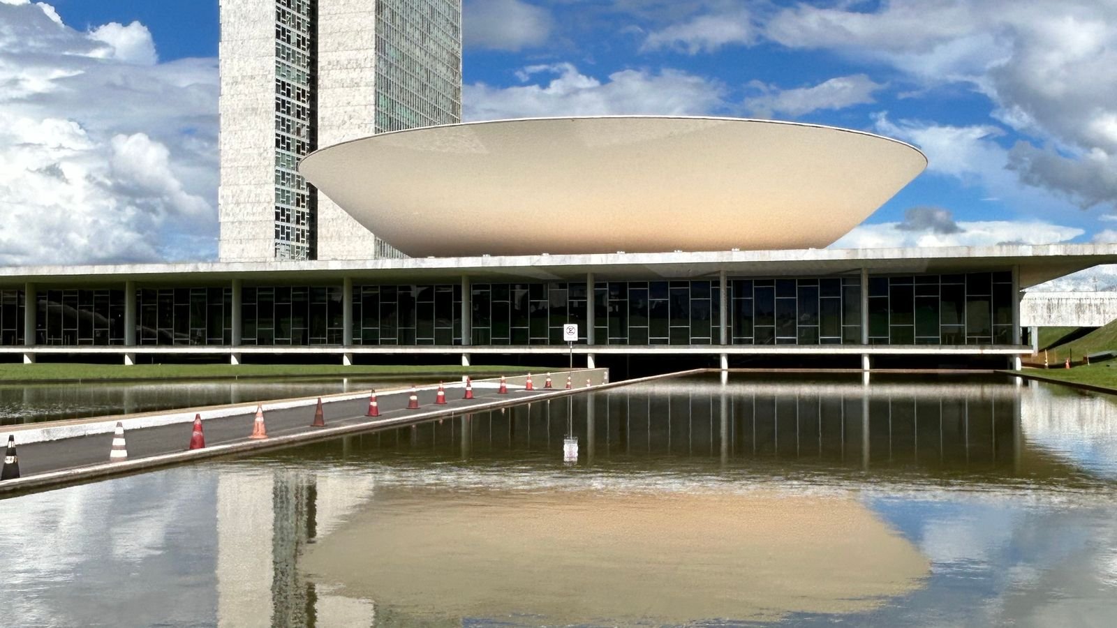 Fachada do Congresso Nacional em Brasília com o domo do Senado refletido no espelho d'água