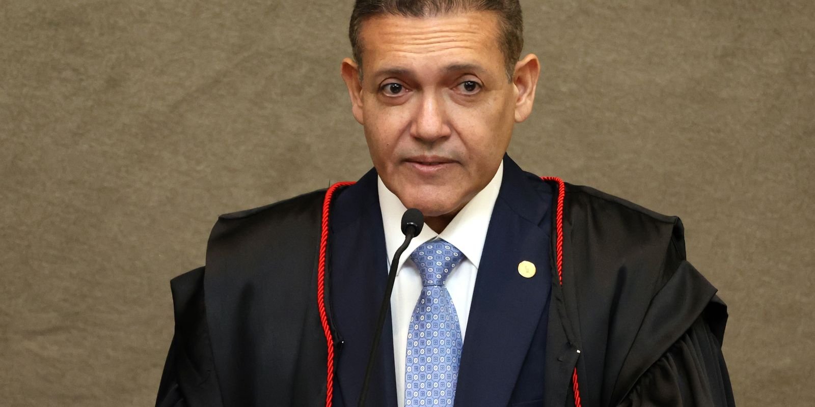 O ministro Kassio Nunes Marques, presidente do TSE, de toga, diante de um microfone