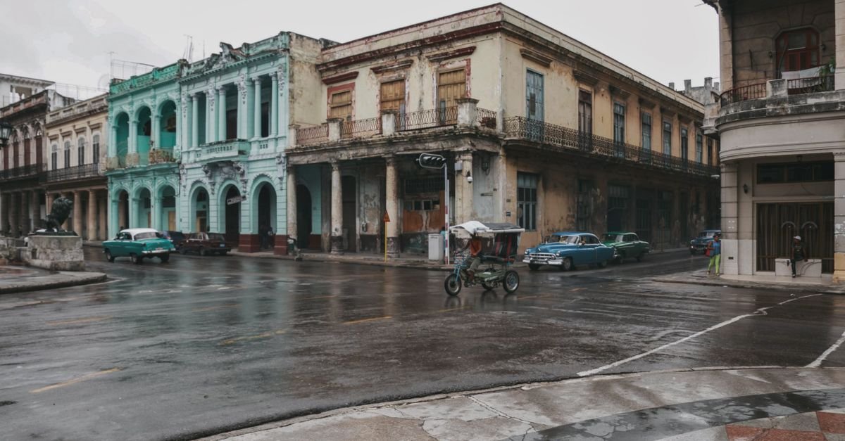 Rua de Havana com prédios antigos e carros clássicos após a chuva