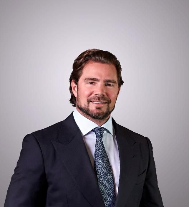 Retrato do empresário Daniel Vorcaro, de terno escuro e gravata, em fundo neutro