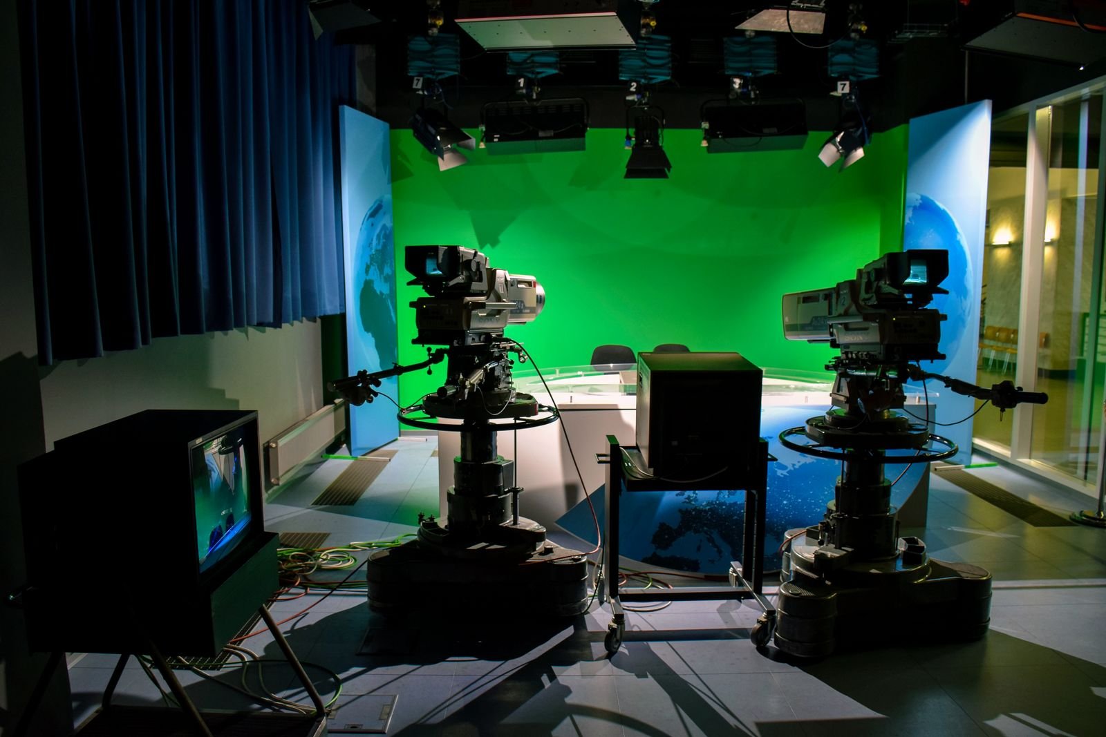 Estúdio de televisão com duas câmeras profissionais e cenário de fundo verde