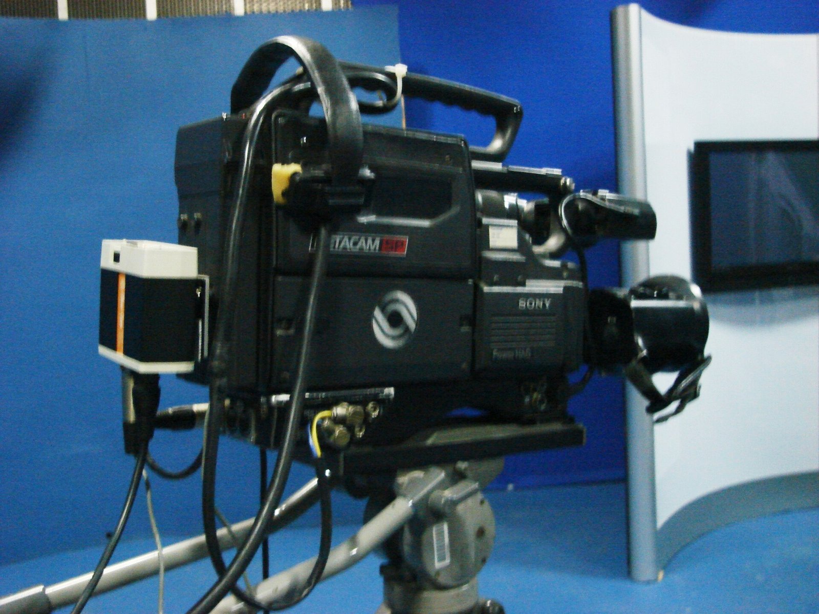 Câmera de televisão posicionada em estúdio com fundo azul