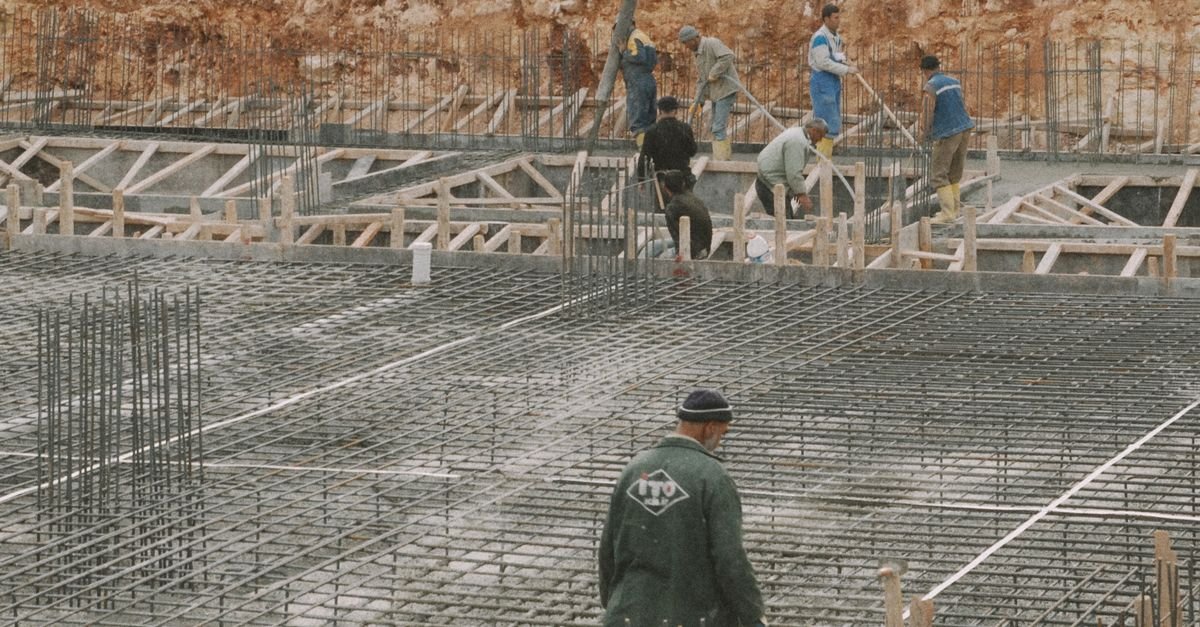 Trabalhadores montando fundação com vergalhões de aço em canteiro de obras