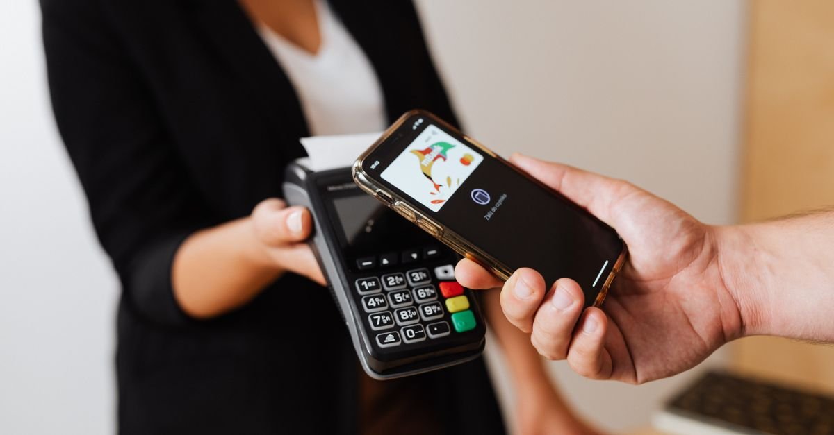 Pessoa aproxima celular de máquina de cartão para pagamento digital