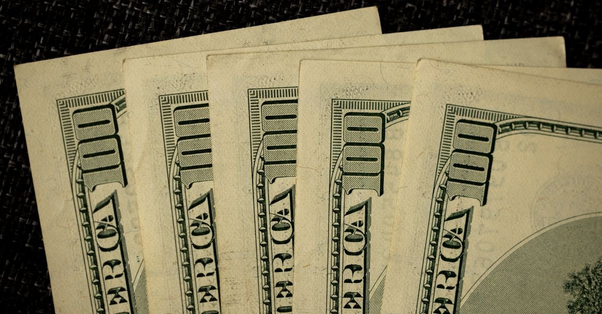 Notas de cem dólares americanos dispostas sobre superfície escura