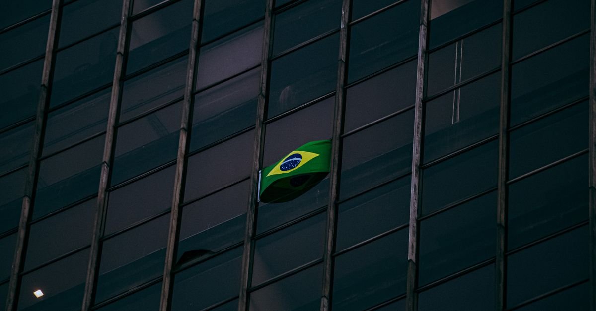 Bandeira do Brasil hasteada na fachada de vidro de um edificio
