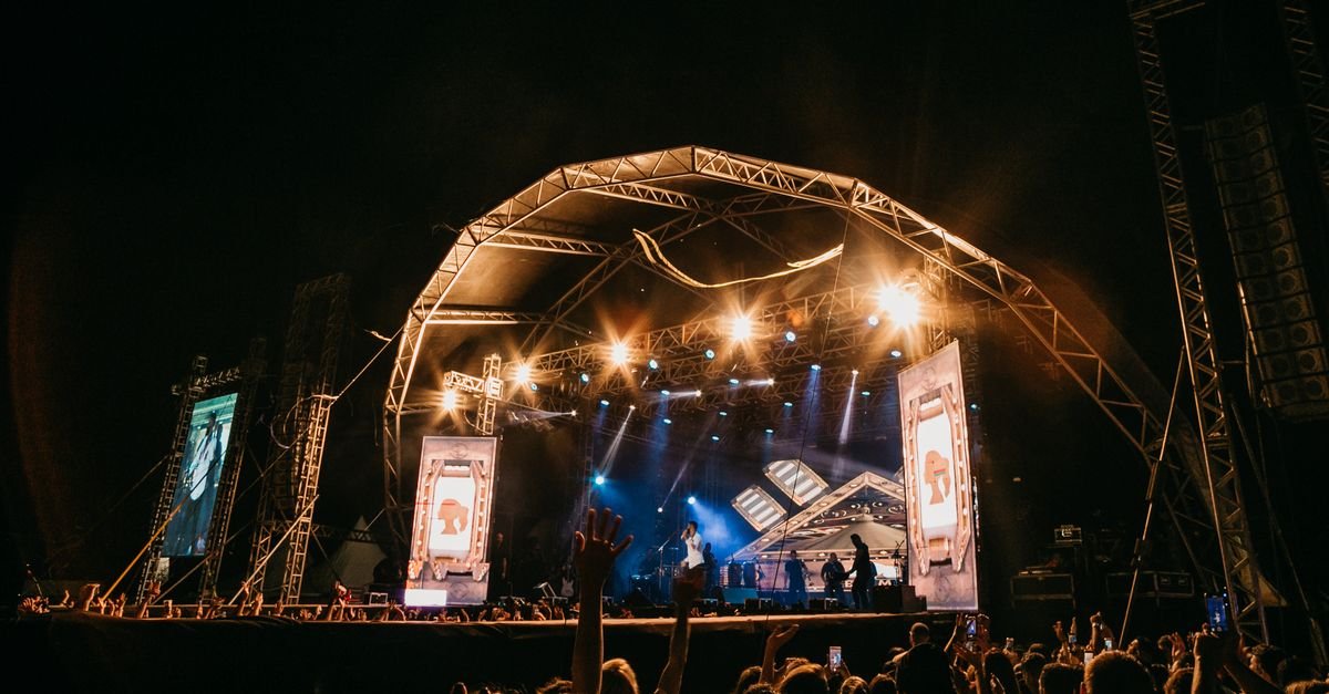 Palco de show ao ar livre iluminado durante apresentação noturna