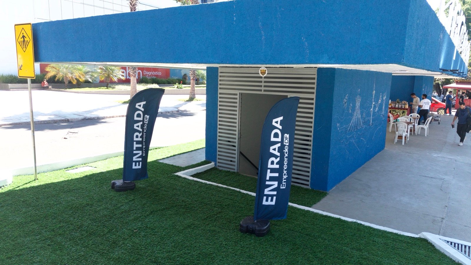 Bandeiras de entrada do hub EmpreendeDF diante do acesso ao prédio em Brasília