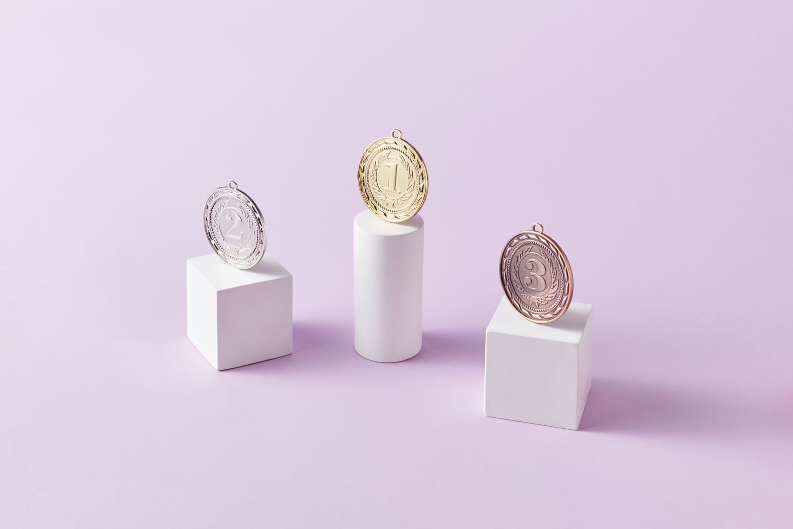 Medalhas de ouro, prata e bronze sobre pedestais brancos (foto ilustrativa)