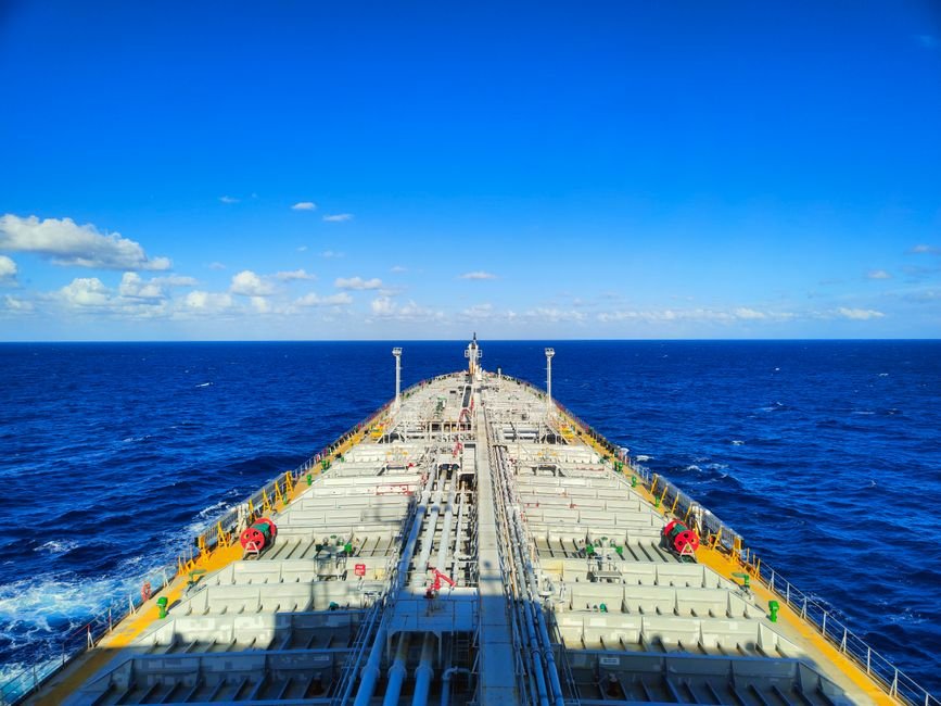 Vista da proa de um navio-tanque carregado navegando em mar aberto sob ceu azul