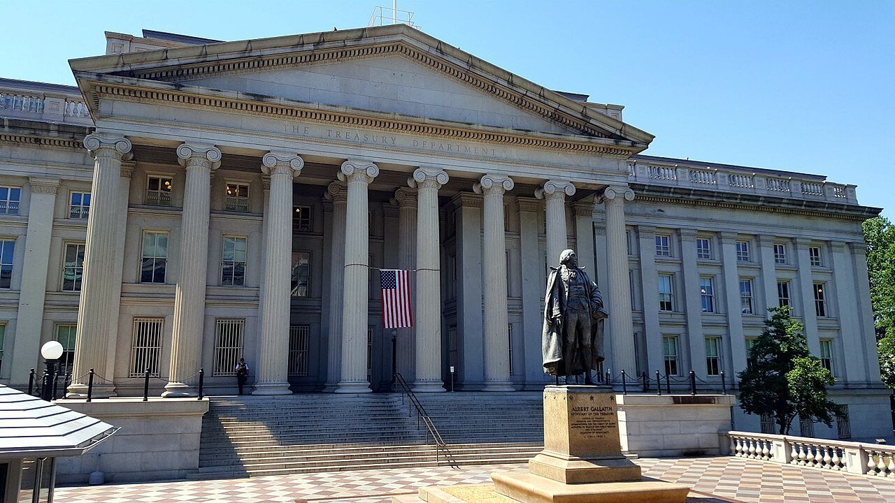 Fachada do prédio do Departamento do Tesouro dos Estados Unidos, em Washington, com bandeira americana e a estátua de Albert Gallatin