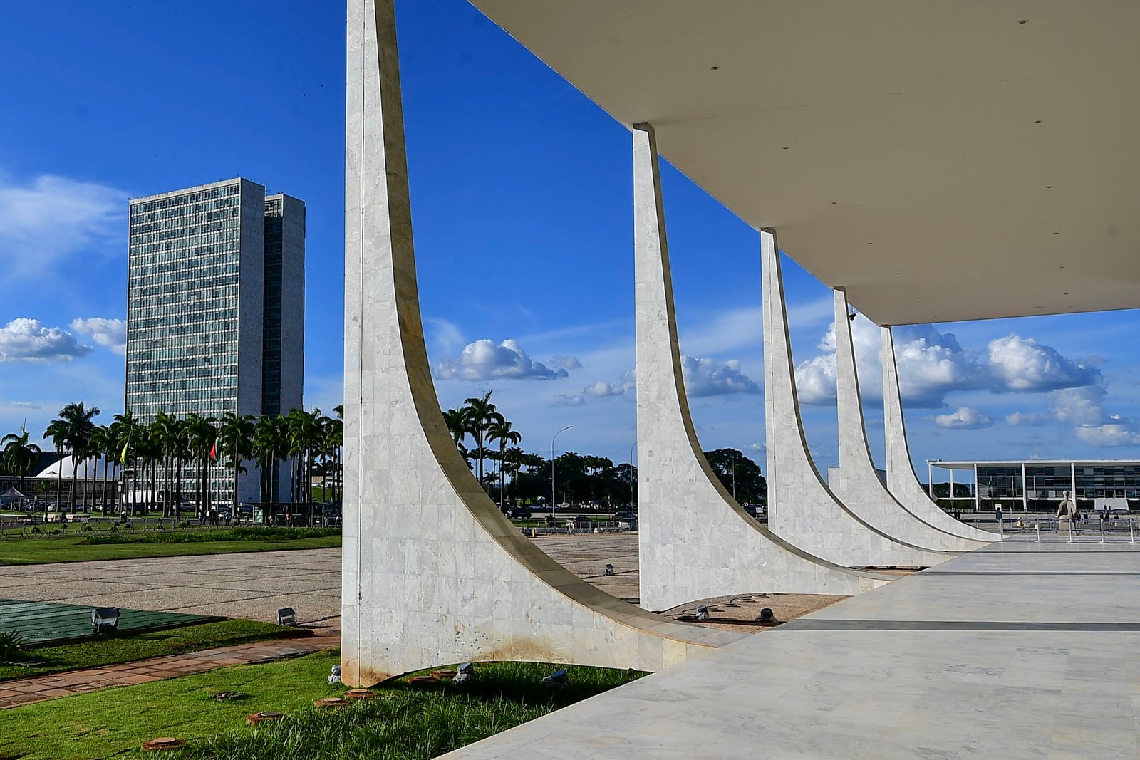 Colunas curvas de mármore da fachada do Supremo Tribunal Federal, com o Congresso Nacional ao fundo
