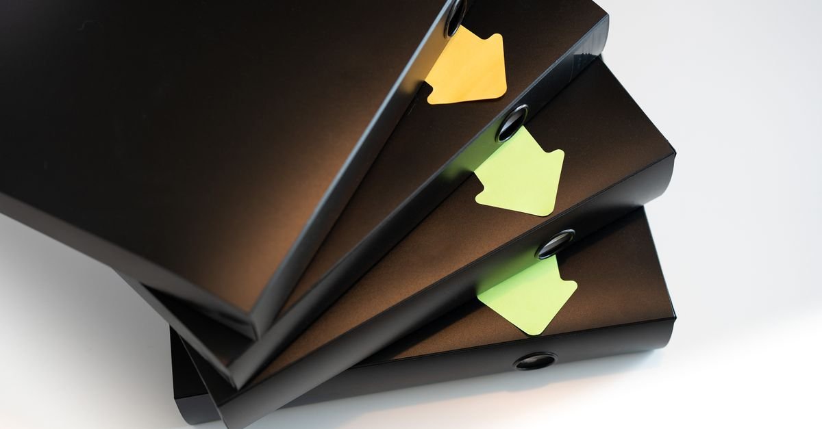 Pilha de fichários pretos com etiquetas coloridas