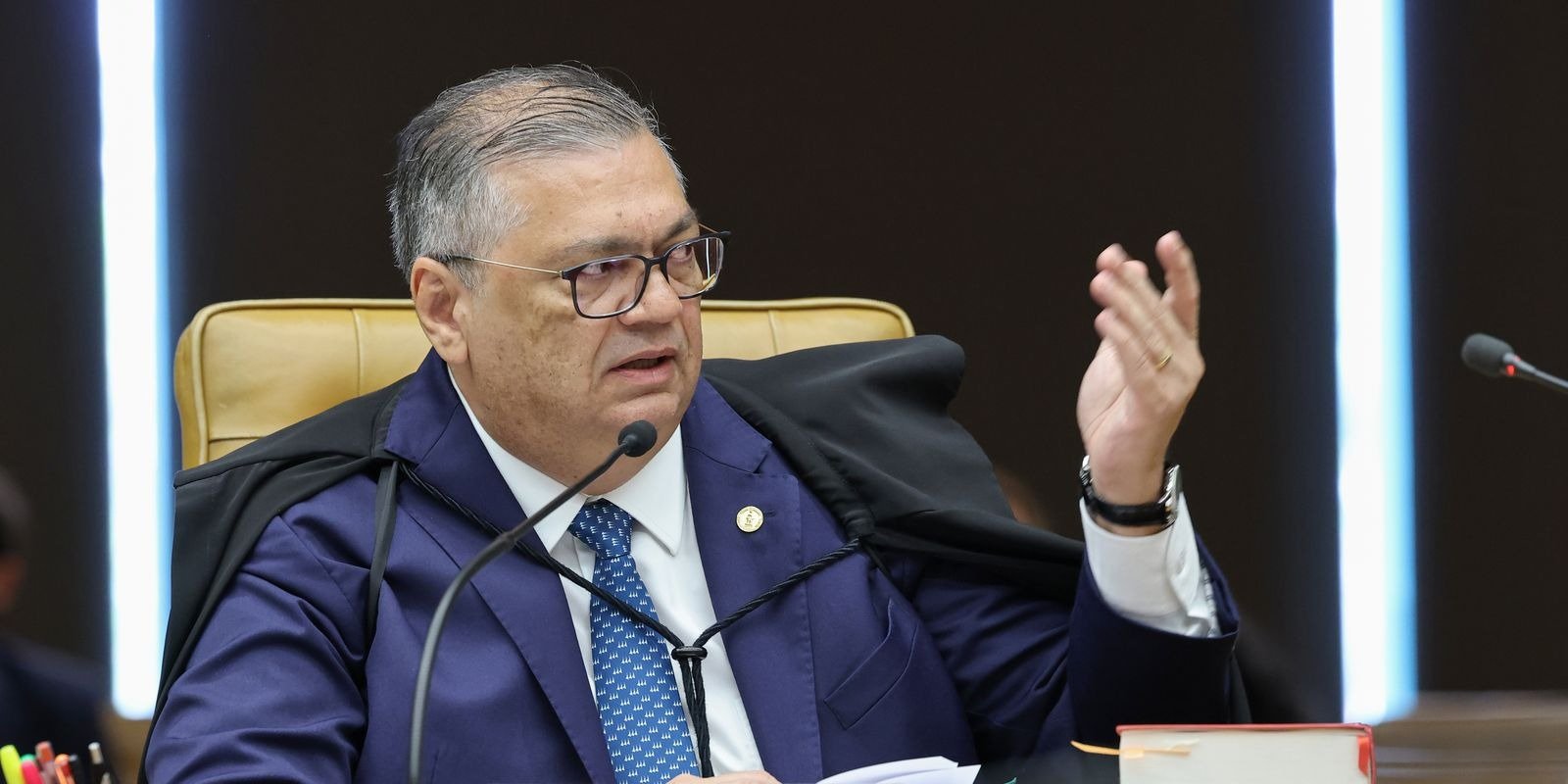 O ministro Flávio Dino, de toga, gesticula ao falar ao microfone durante sessão no plenário do Supremo Tribunal Federal