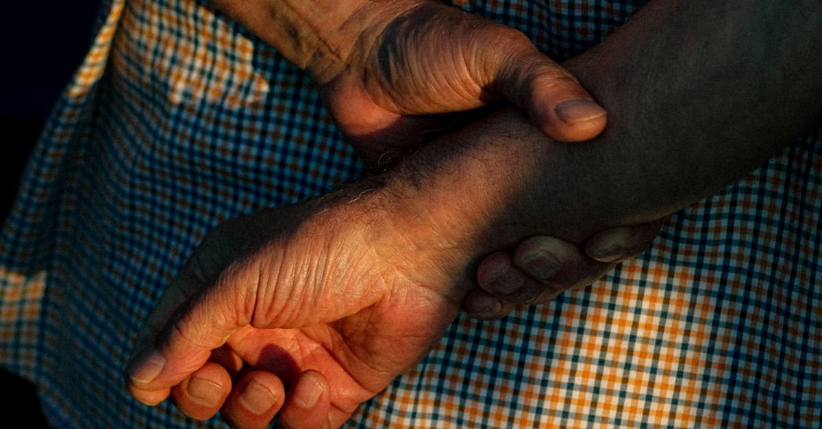 Mãos de pessoa idosa entrelaçadas em close, sem identificação do rosto
