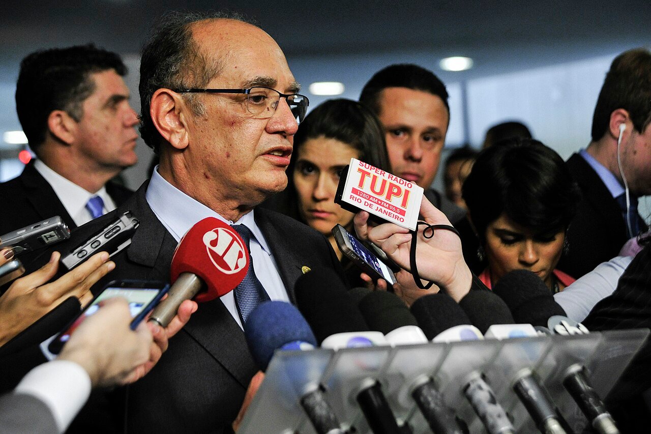 O ministro Gilmar Mendes, do STF, fala a jornalistas cercado por microfones de emissoras brasileiras
