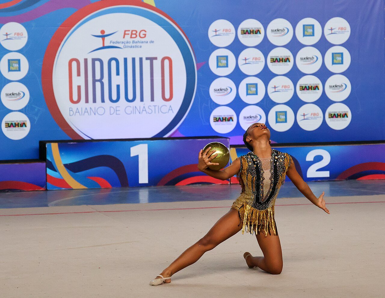 Ginasta executa movimento com a bola durante competição de ginástica rítmica