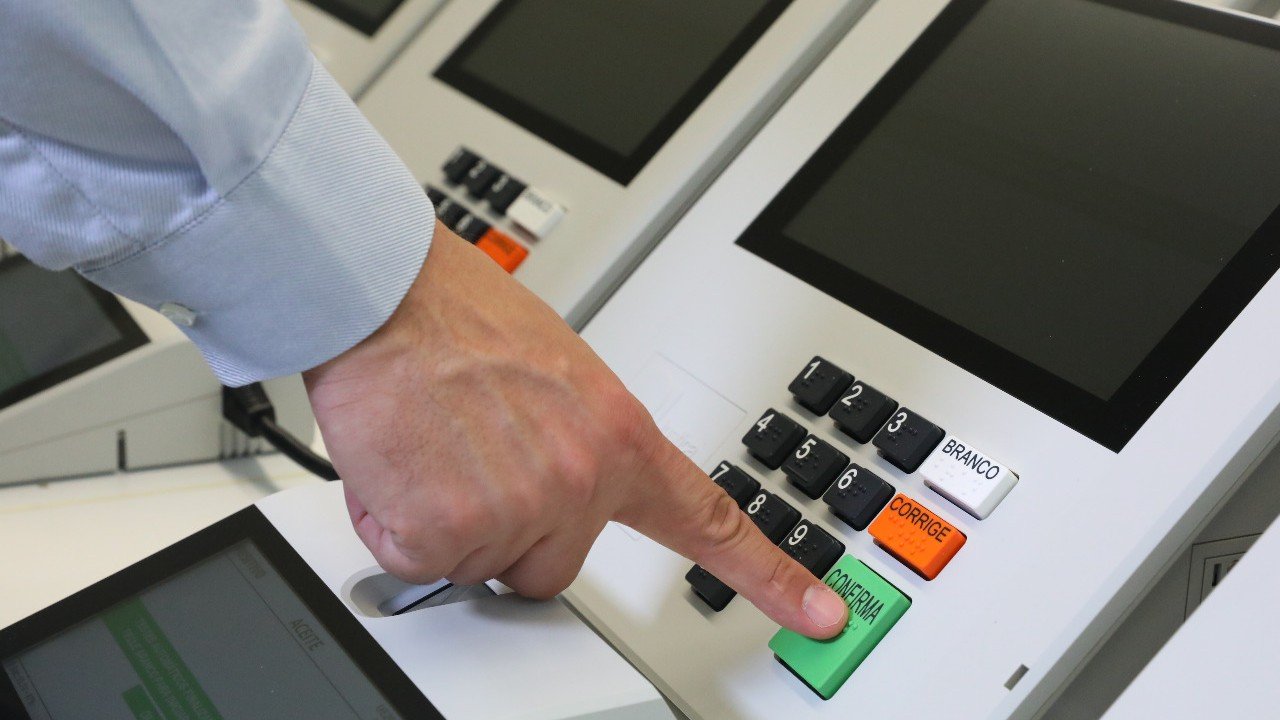 Eleitor aperta a tecla Confirma em uma urna eletrônica brasileira