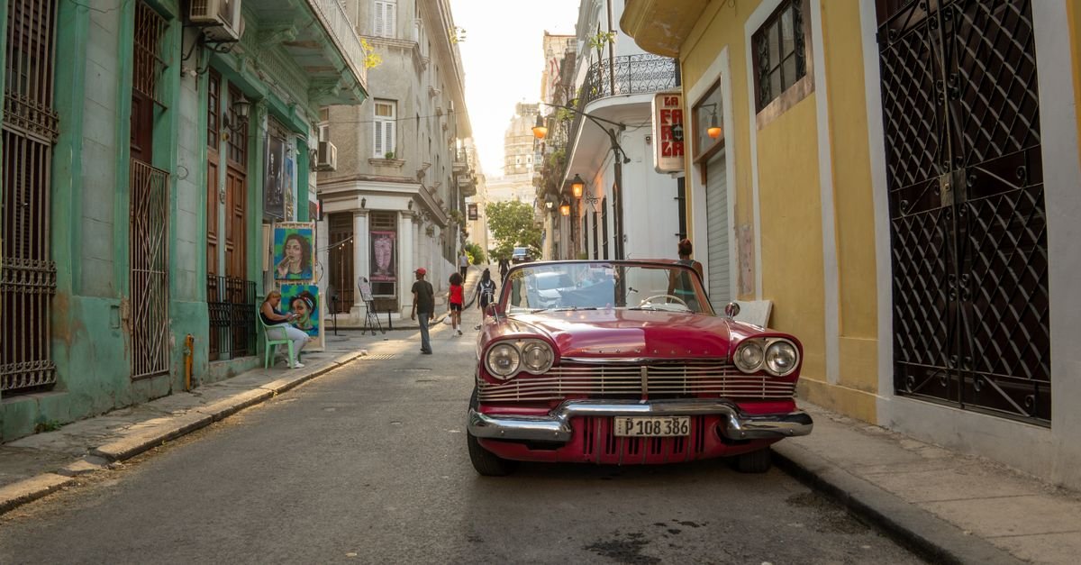 Rua estreita de Havana, em Cuba, com carro clássico estacionado e prédios antigos