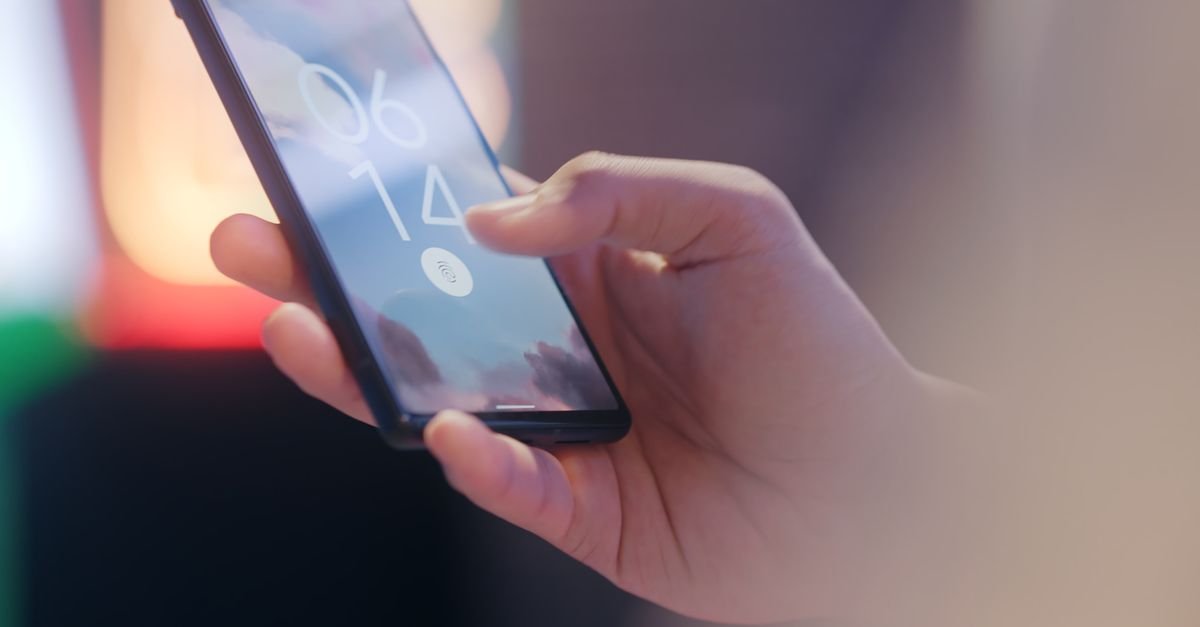 Mão segura celular com ícone de leitor de digital na tela de bloqueio