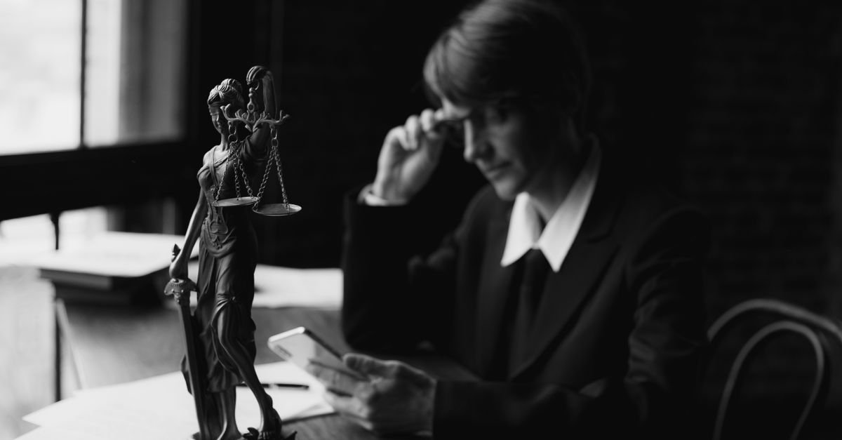 Estátua da Justiça sobre mesa de escritório em imagem em preto e branco