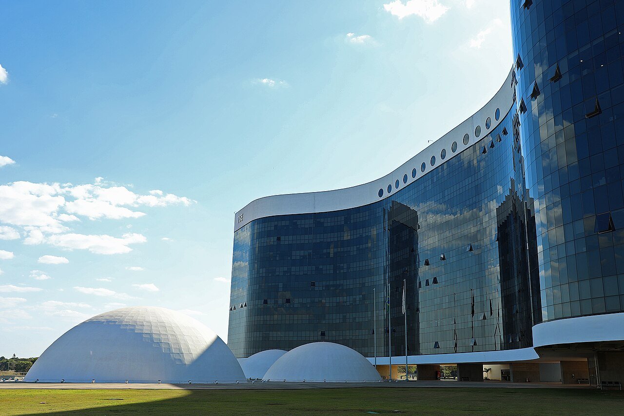 Fachada de vidro do edifício-sede do Tribunal Superior Eleitoral em Brasília sob céu azul