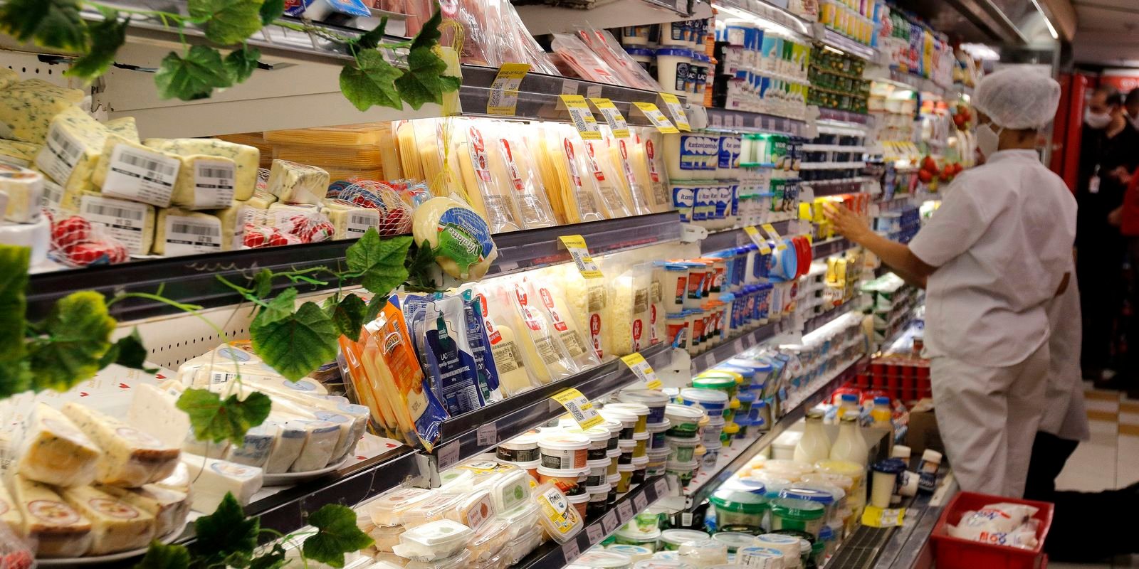 Prateleira de laticínios e queijos em supermercado, com etiquetas de preço nas gôndolas