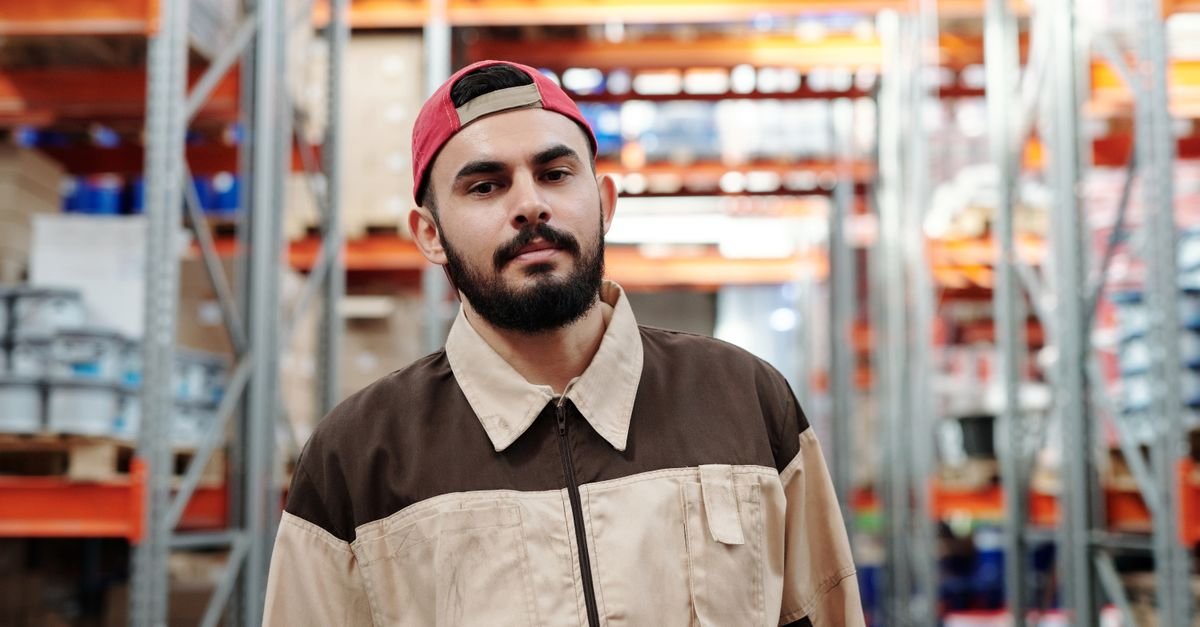 Jovem trabalhador de uniforme em galpão de logística