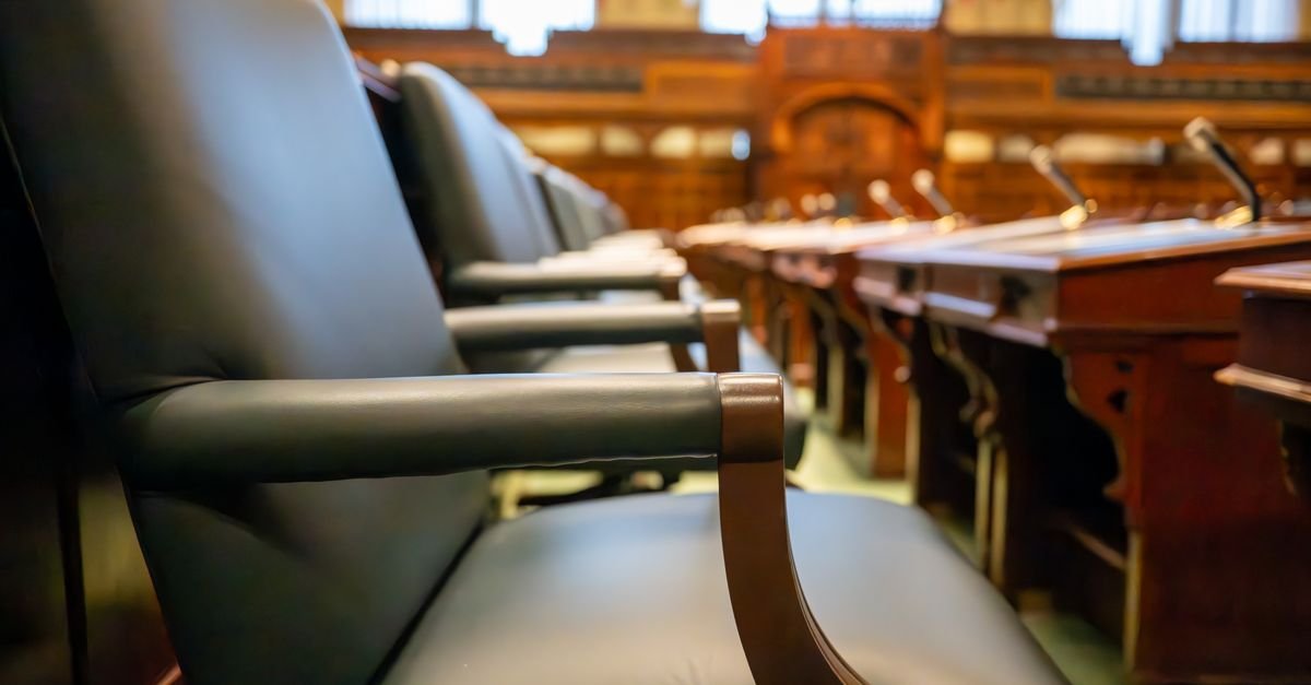 Poltronas de couro e bancadas de madeira em sala de sessões vazia