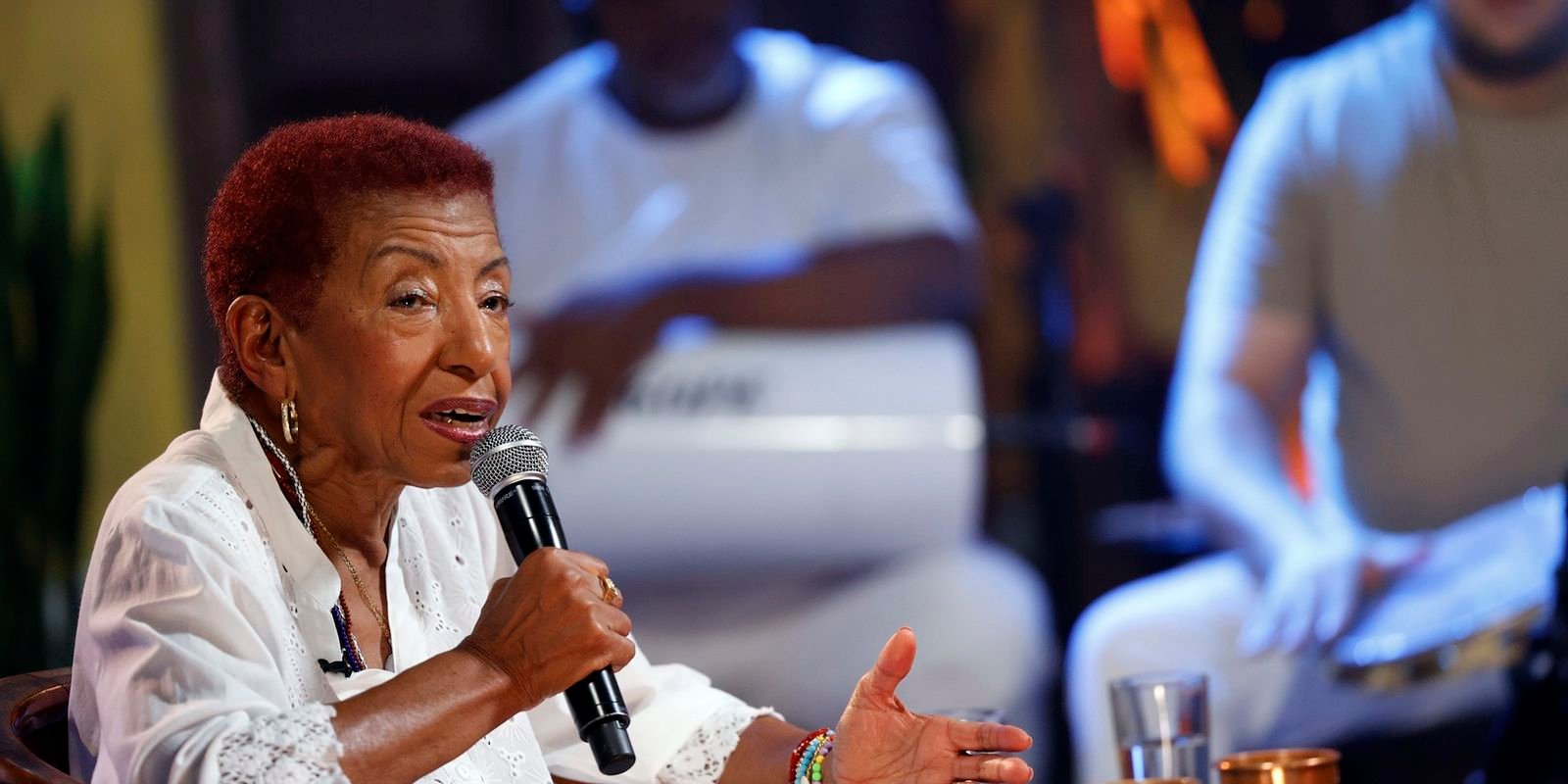 A cantora Leci Brandão fala ao microfone durante gravação de programa de televisão