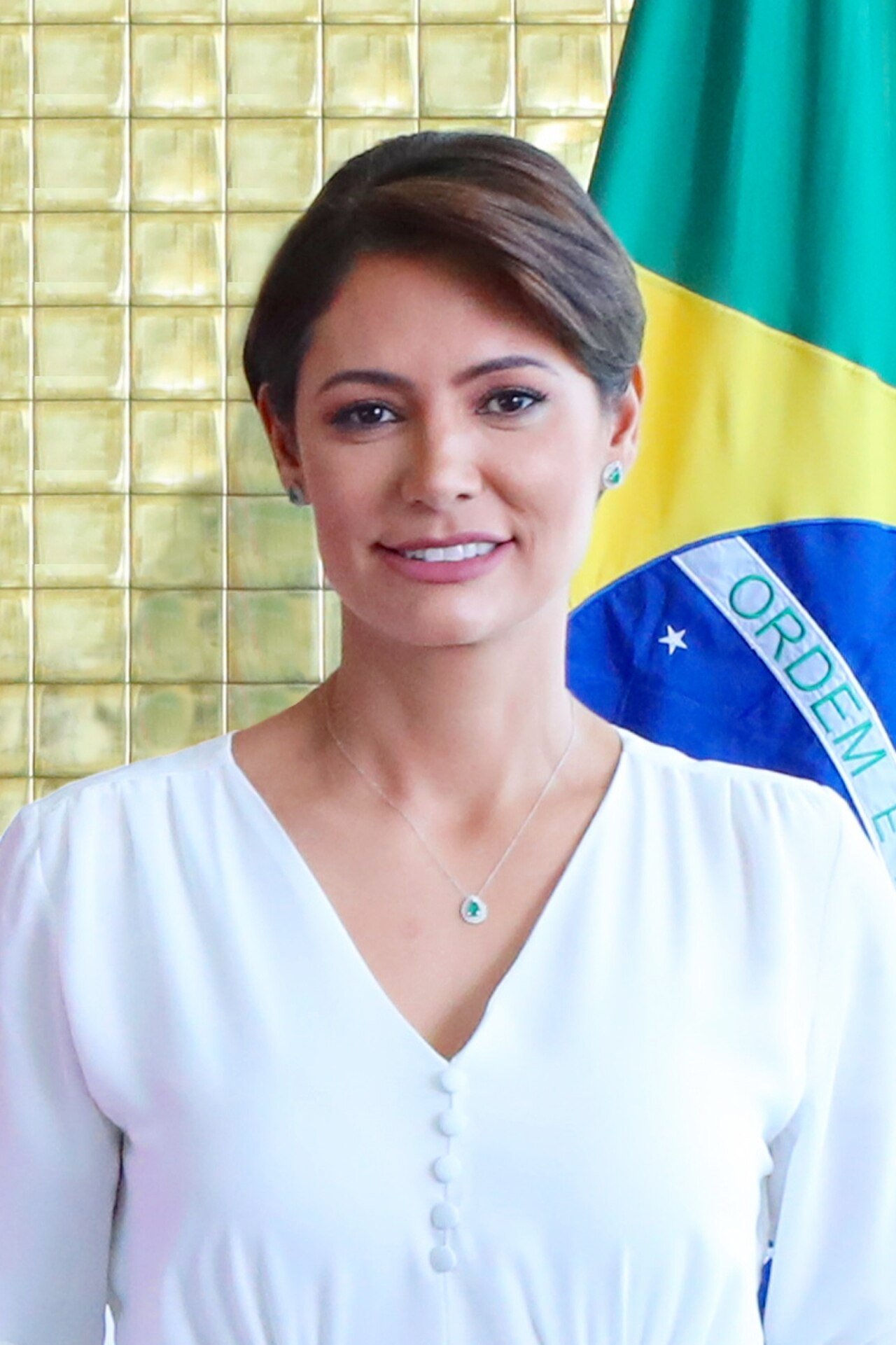 Michelle Bolsonaro em retrato oficial, ao lado da bandeira do Brasil