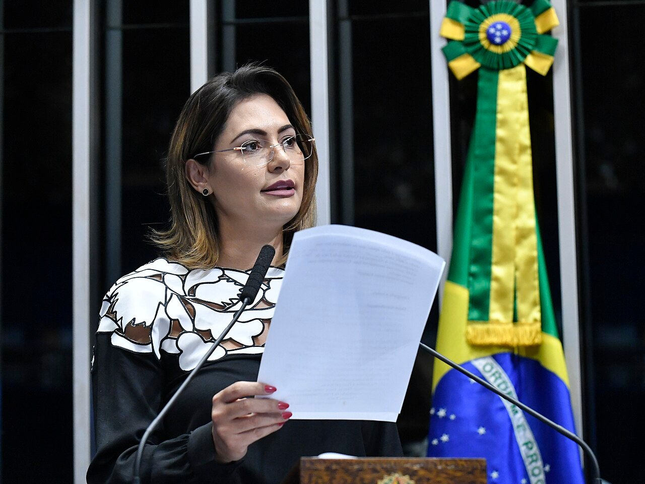 Michelle Bolsonaro discursa na tribuna do Senado, com a bandeira do Brasil ao fundo